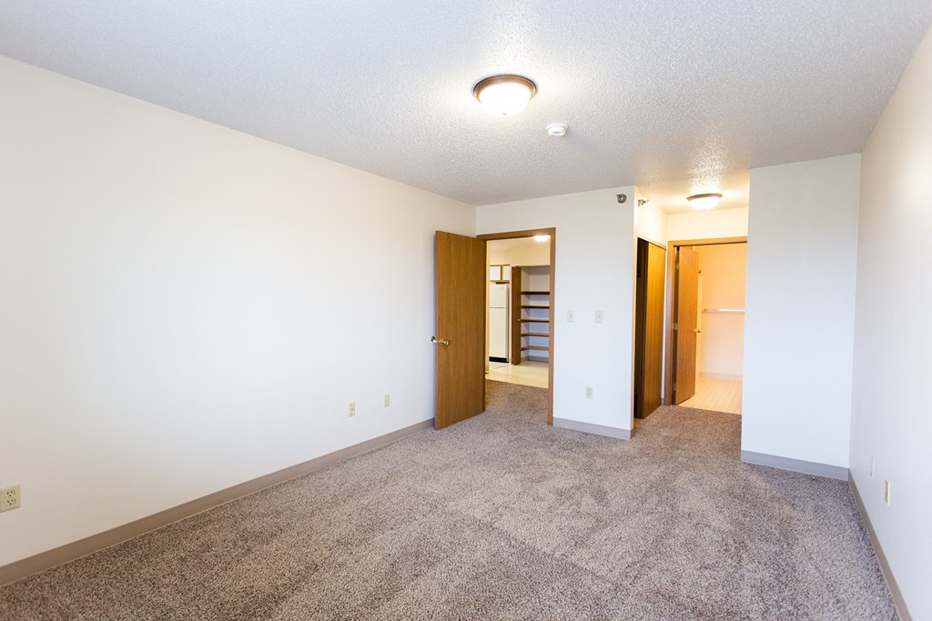 an empty living room with carpet and a door to a hallway