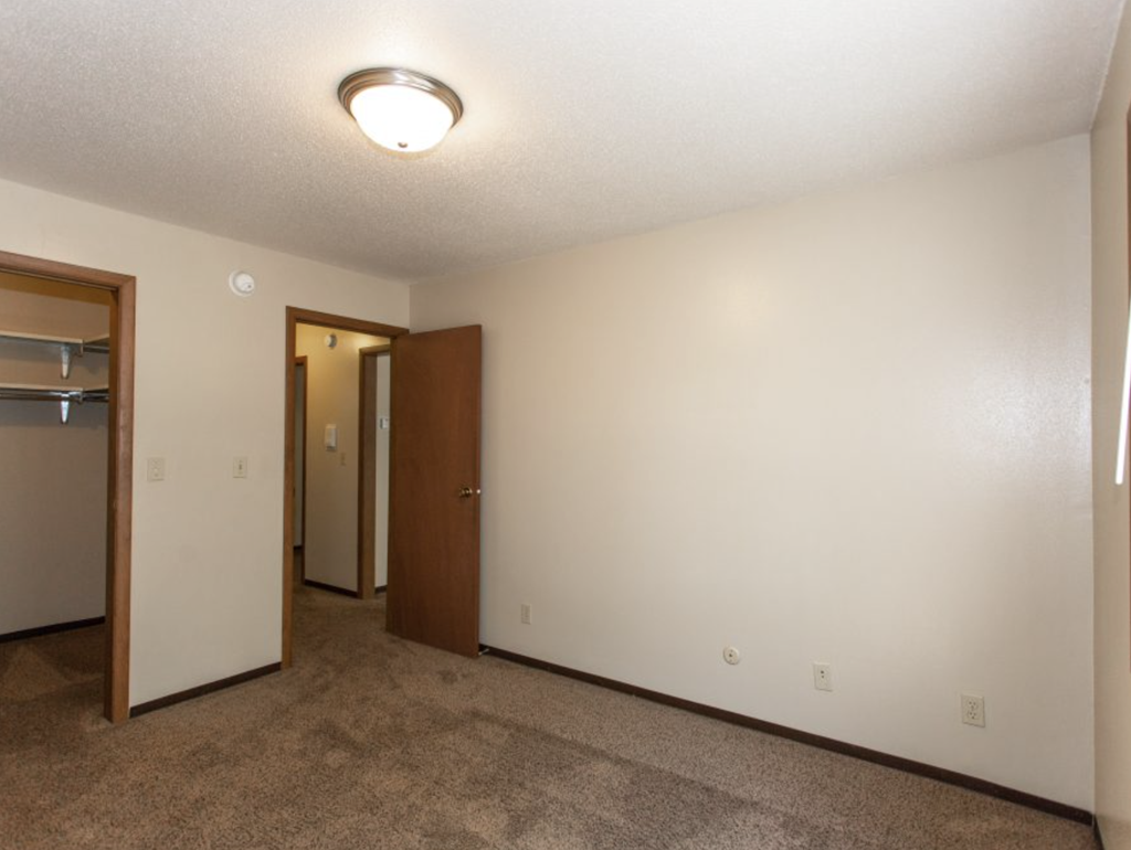 the living room of an empty apartment with a door to the hallway