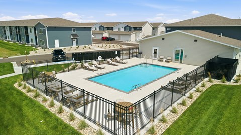 A black fence surrounds a blue swimming pool.