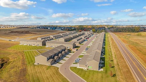 A large, modern building complex sits in a grassy field with a road running in front of it.