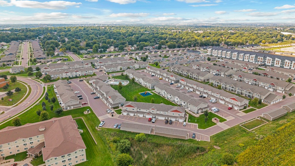 A bird's eye view of a residential area with multiple houses and a parking lot.