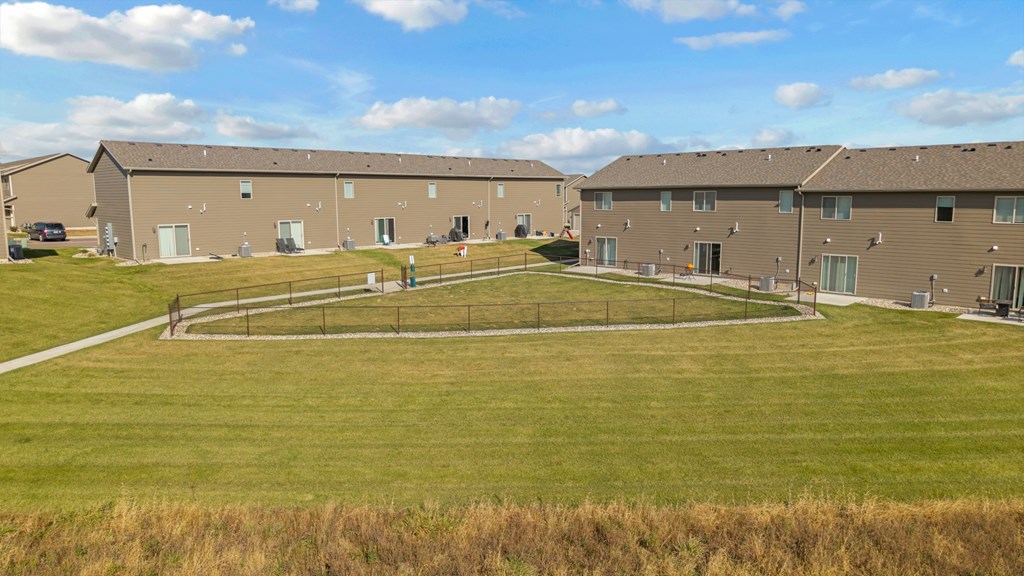 A large grassy field in front of a building complex.