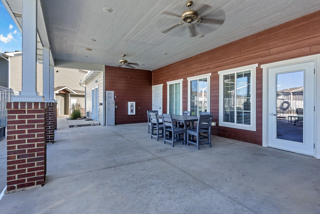 A patio with a table and chairs is covered by a roof.