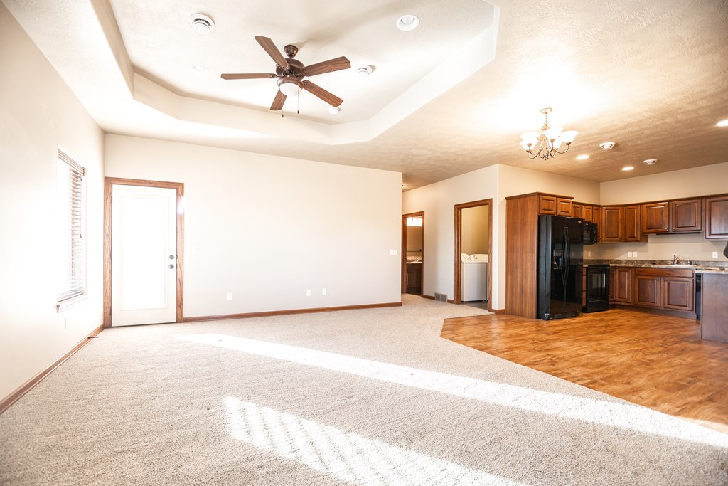 an empty living room and kitchen with a ceiling fan