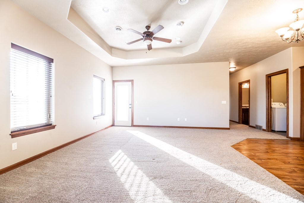 an empty living room with a ceiling fan and window