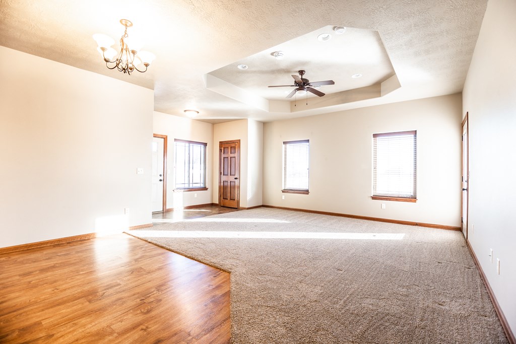 an empty living room with wood floors and a ceiling fan