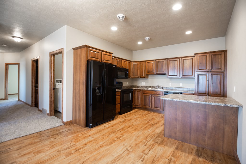 a kitchen with wooden cabinets and a black refrigerator