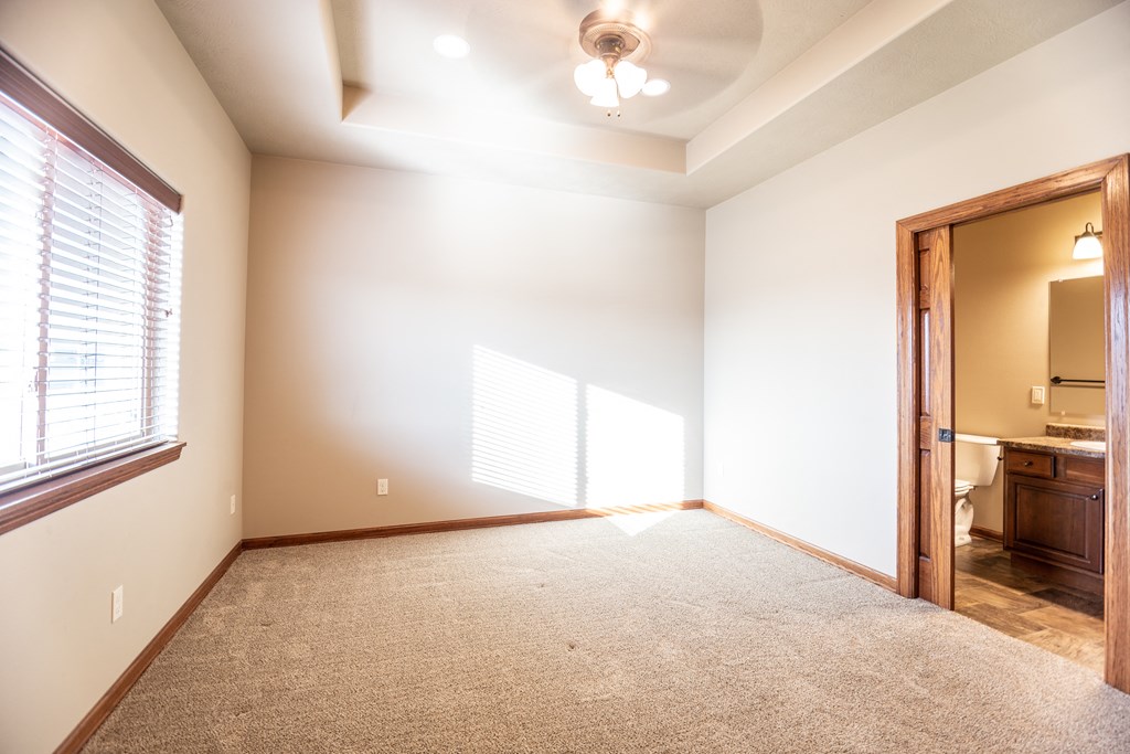 an empty living room with a large window and a door to a bathroom