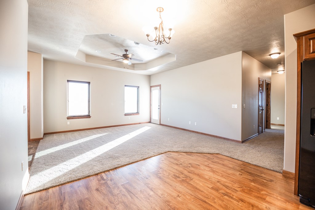 an empty living room with wood floors and a ceiling fan
