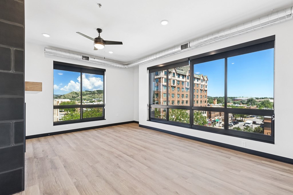 A room with a ceiling fan and a view of a building outside the window.
