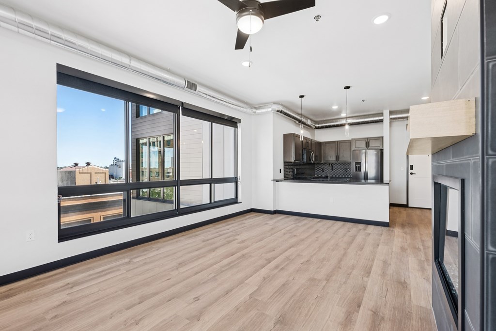 A spacious room with a ceiling fan and a view of the city through the windows.