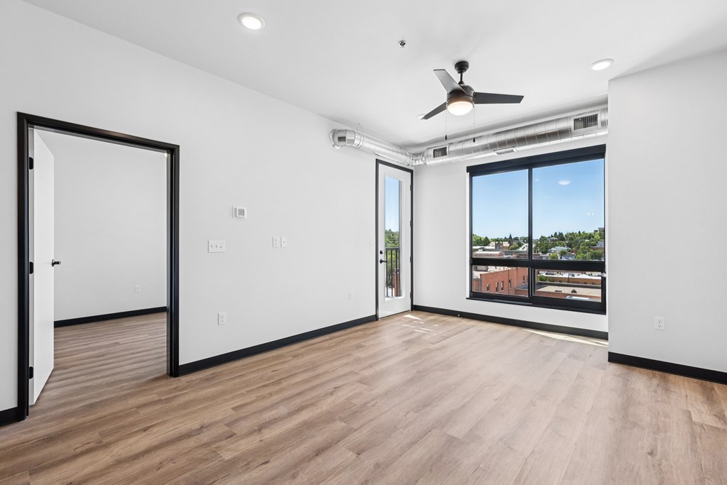 A room with a ceiling fan and a window overlooking a cityscape.