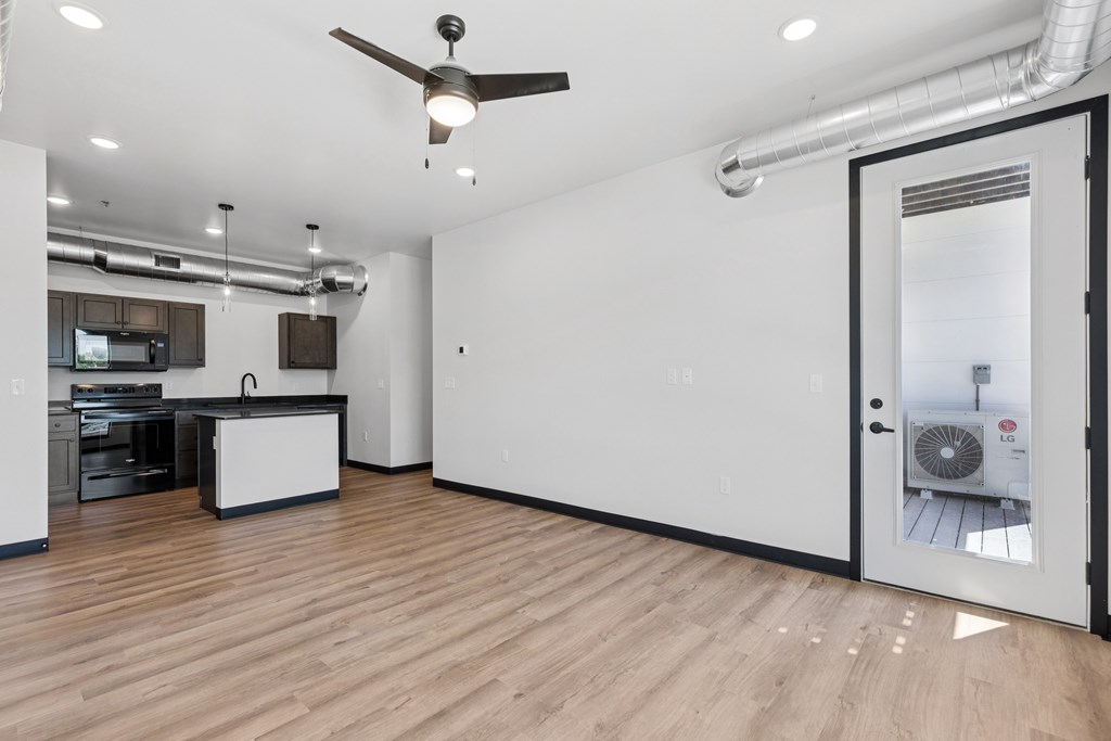 A room with a ceiling fan and a kitchen area.