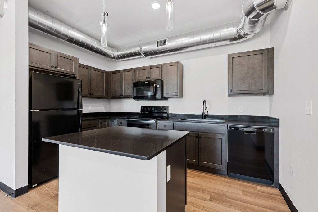 A modern kitchen with a black refrigerator and stove.