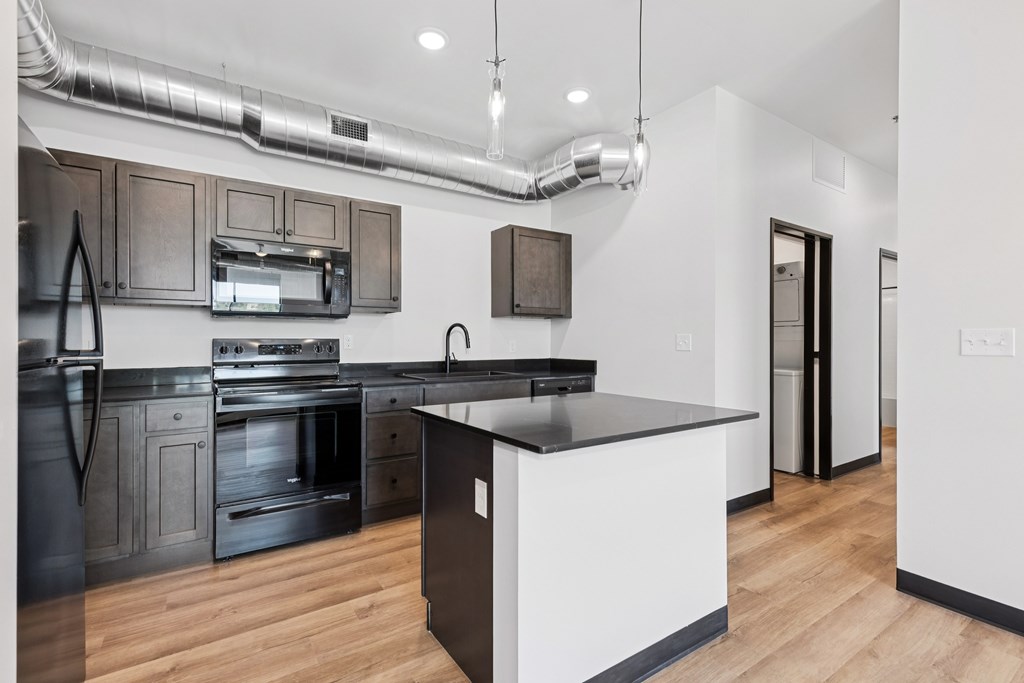 A modern kitchen with a black countertop and stainless steel appliances.