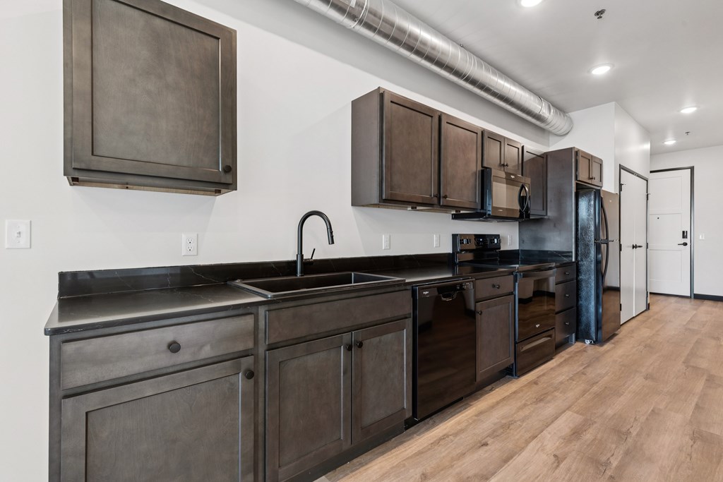 A kitchen with dark wood cabinets and a black countertop.