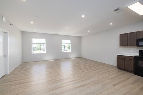 A spacious room with wooden flooring and two windows.