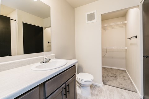 A white toilet sits in a bathroom with a sink and mirror.