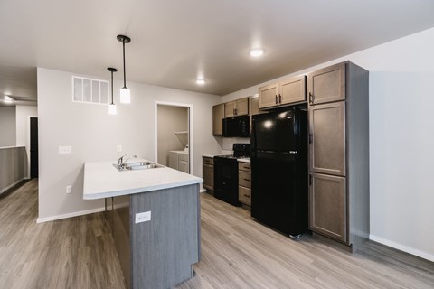 A kitchen with a black refrigerator and a white counter top.