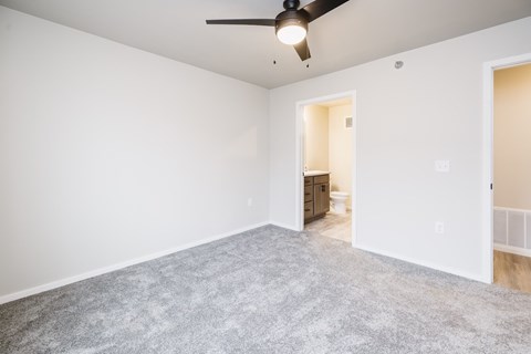 A room with a ceiling fan and carpeted floor.