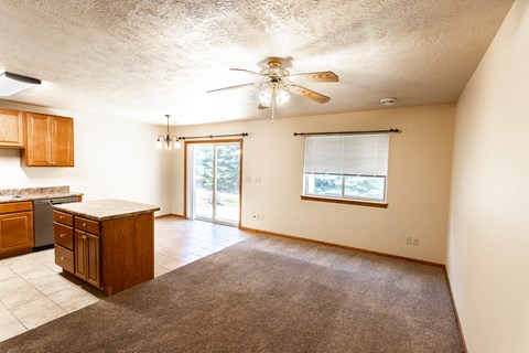 an empty kitchen and living room with a ceiling fan