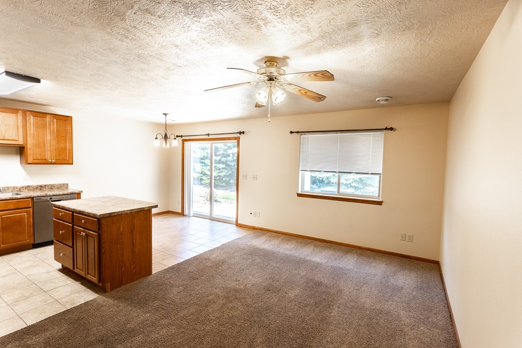 an empty kitchen and living room with a ceiling fan