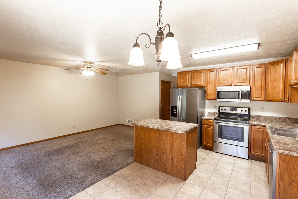 an empty kitchen with wooden cabinets and stainless steel appliances