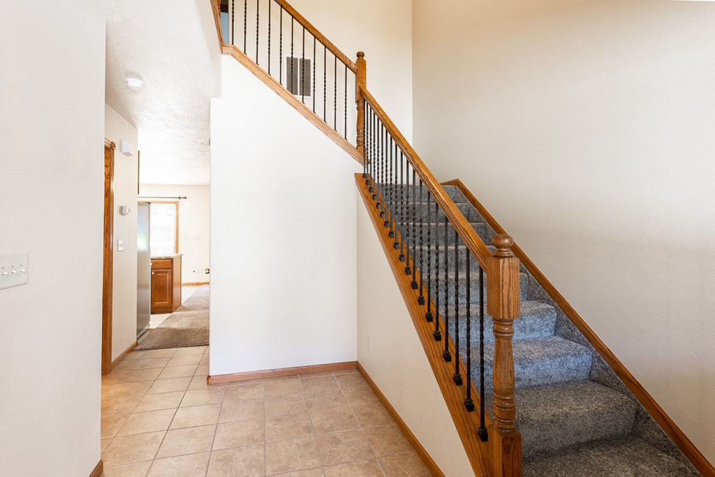 a staircase in a house with a carpeted floor and a hallway with a door