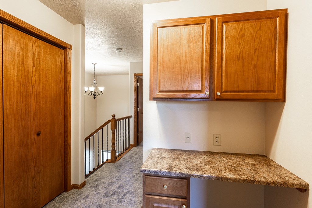 an empty kitchen with wooden cabinets and a staircase