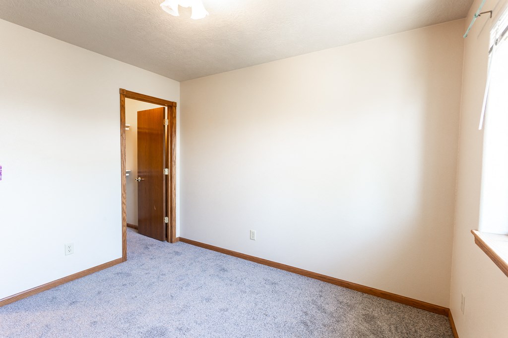 an empty room with white walls and a door to a closet