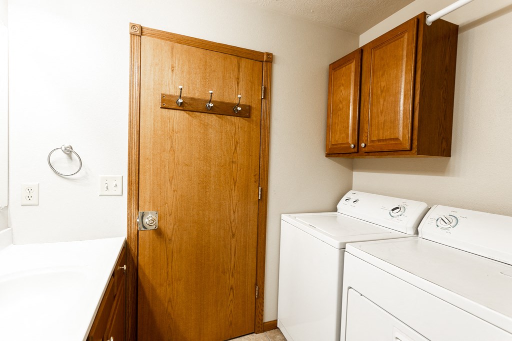 a laundry room with a washer and dryer and a wooden door