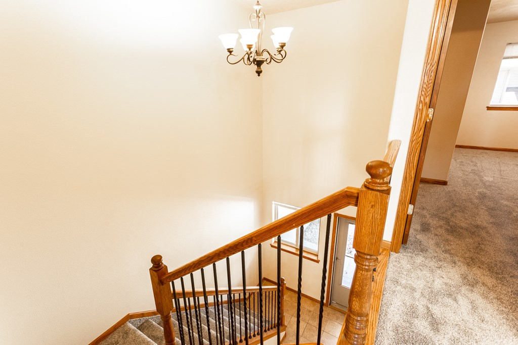 the landing of a staircase in a home with a chandelier