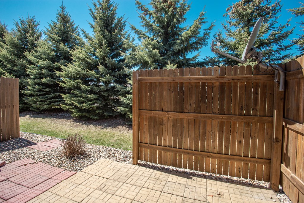 a wooden fence in front of a yard with pine trees