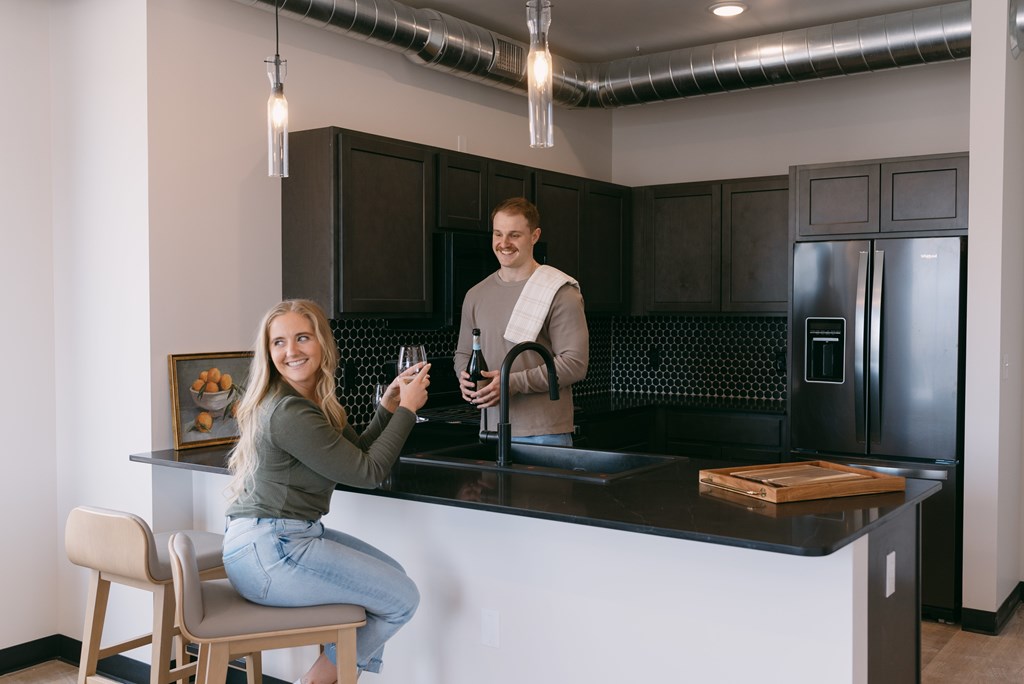 A woman is sitting at a bar with a man behind her.