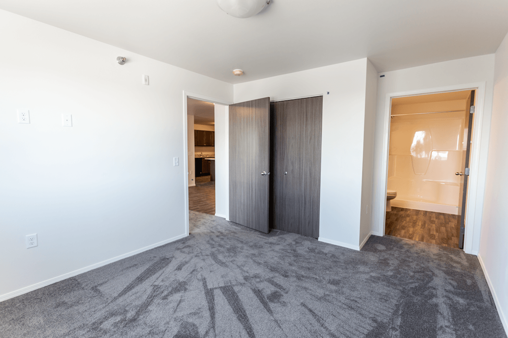 an empty living room with a door to a bathroom and a closet