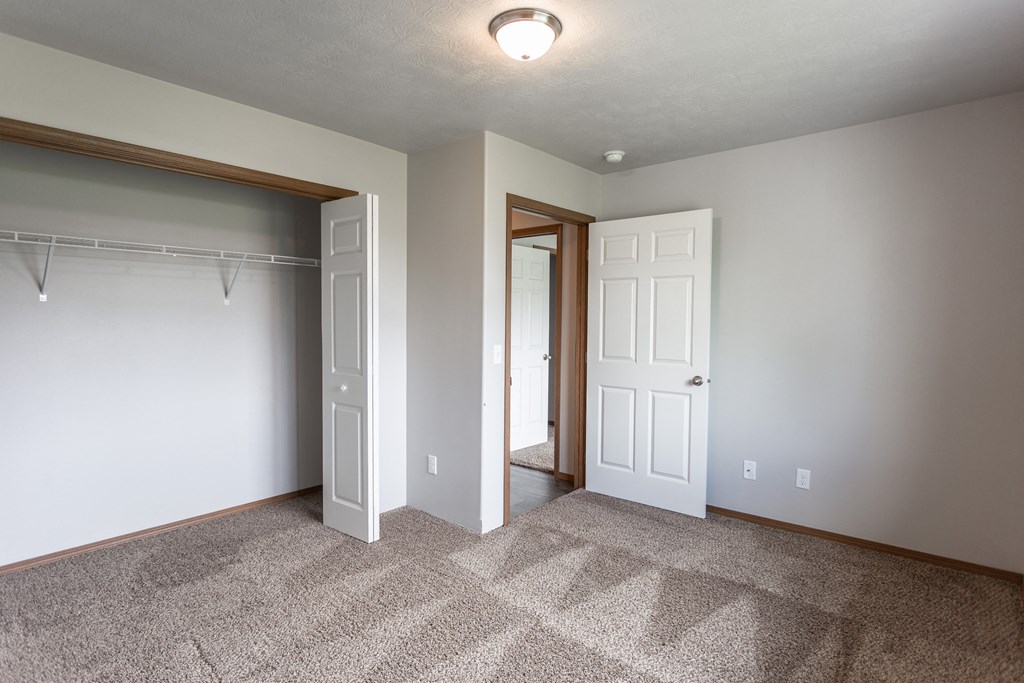 an empty bedroom with a closet and a door to a bathroom