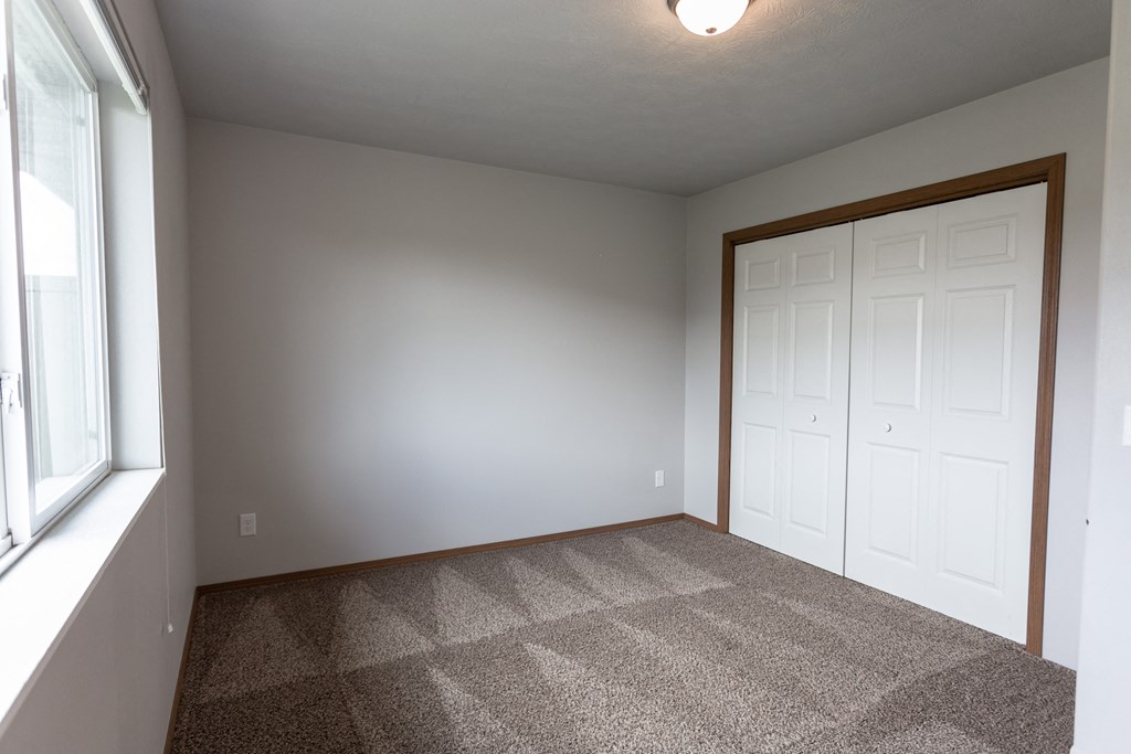 a empty room with carpet and a door to a closet