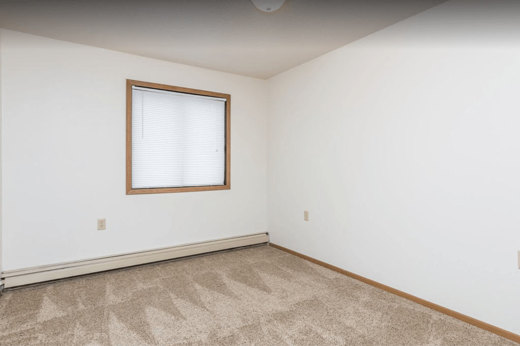 an empty room with a window and white walls