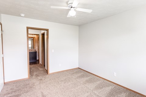 an empty living room with white walls and a ceiling fan