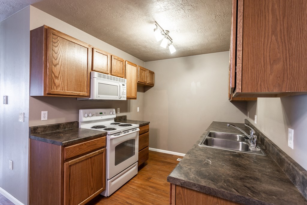 a kitchen with wood cabinets and white appliances and a sink