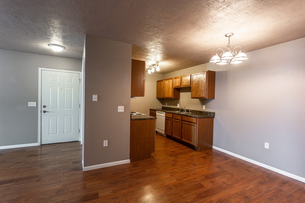 an empty living room and kitchen with wood flooring and