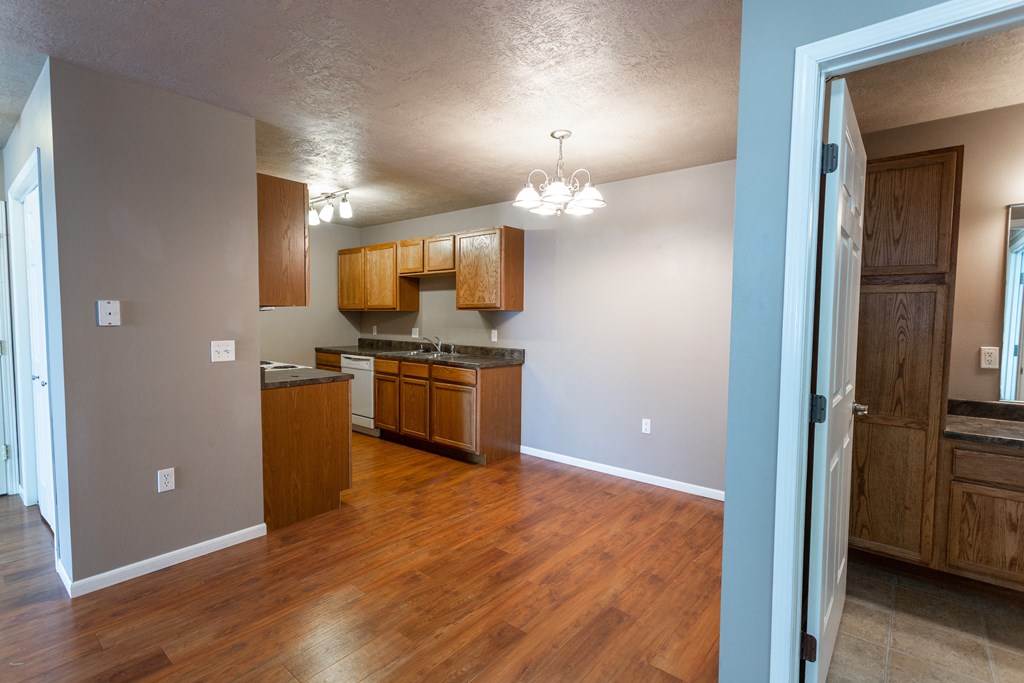 a kitchen and living room with wood flooring and wooden cabinets