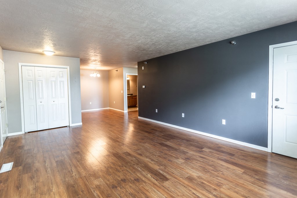 the living room and dining room of an empty house with wood flooring