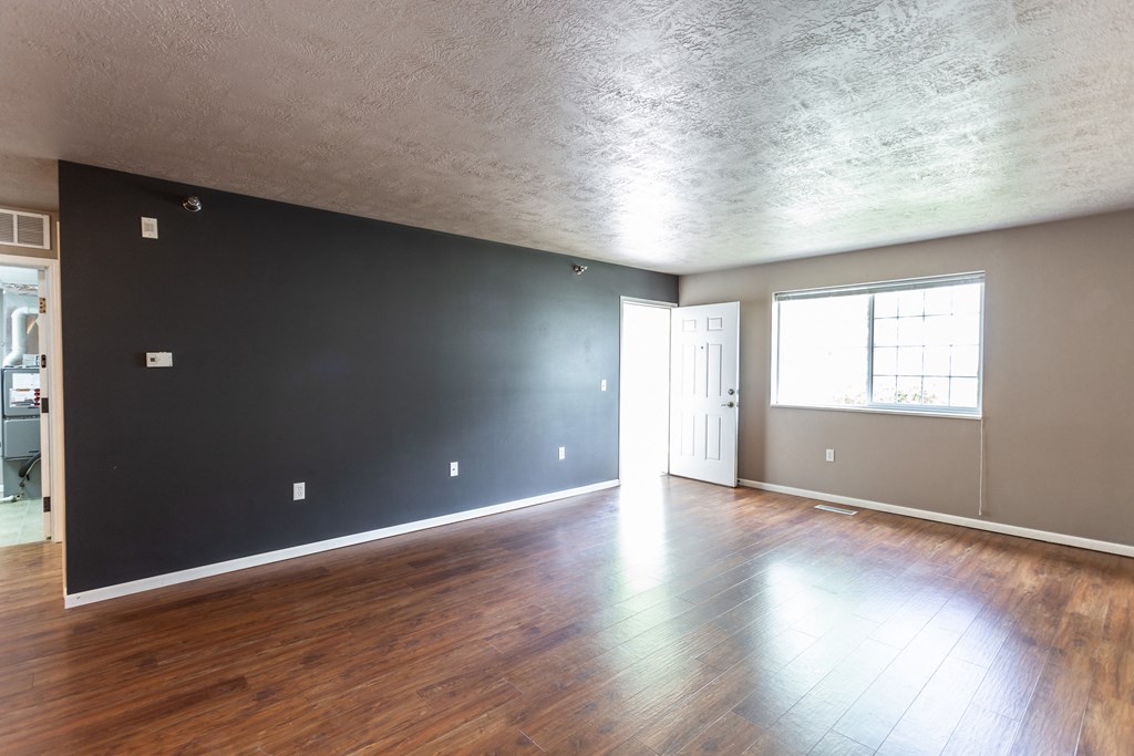 the living room of an empty house with wood floors and grey walls