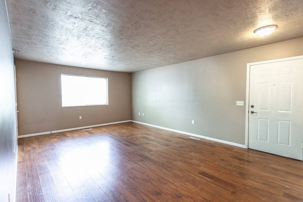 an empty living room with wood floors and a white door