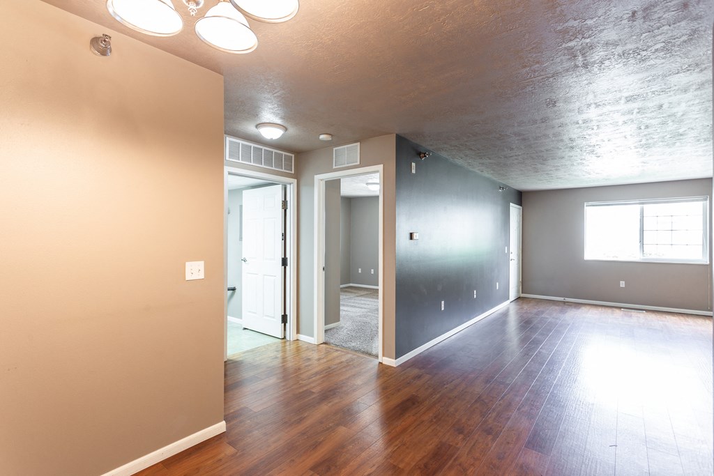 an empty living room with hard wood floors and grey walls