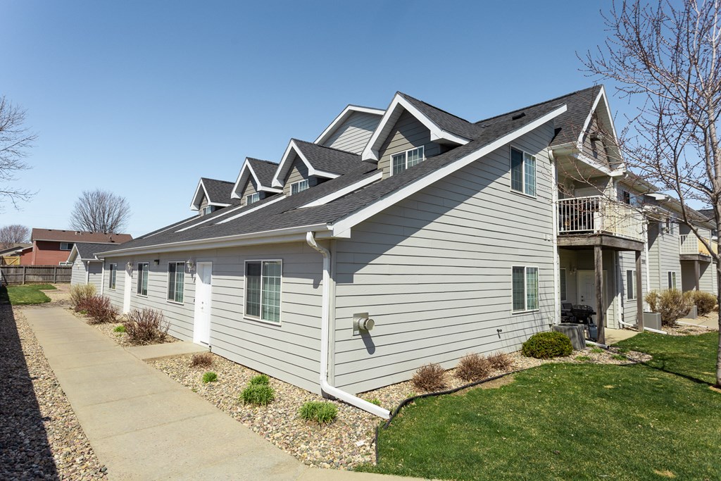 a white house with a gray roof and a sidewalk
