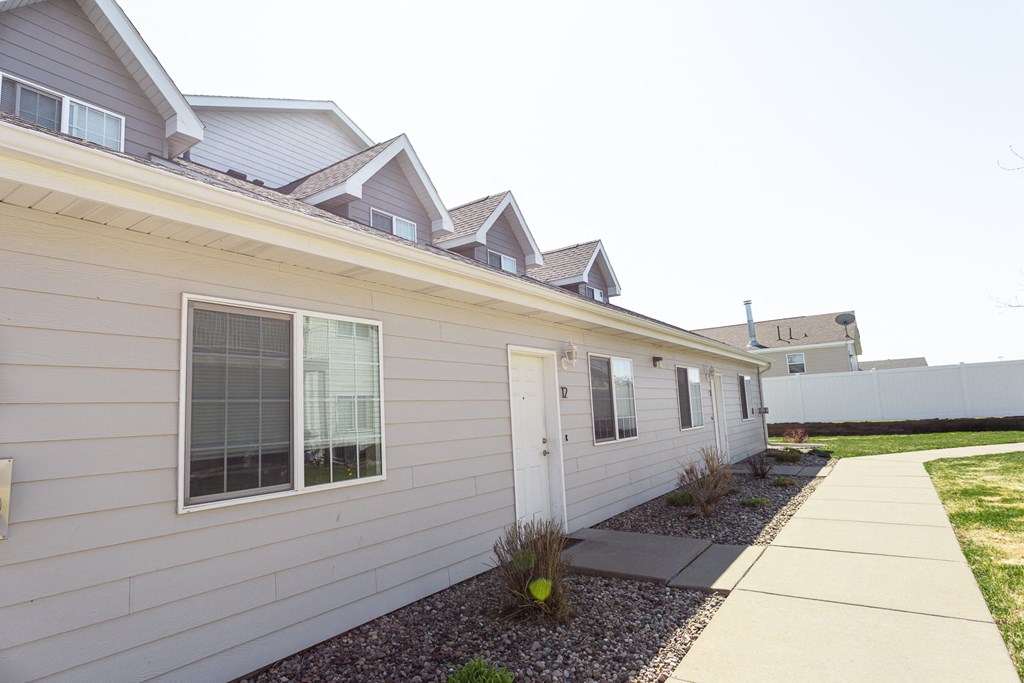 a side view of a white house with a sidewalk