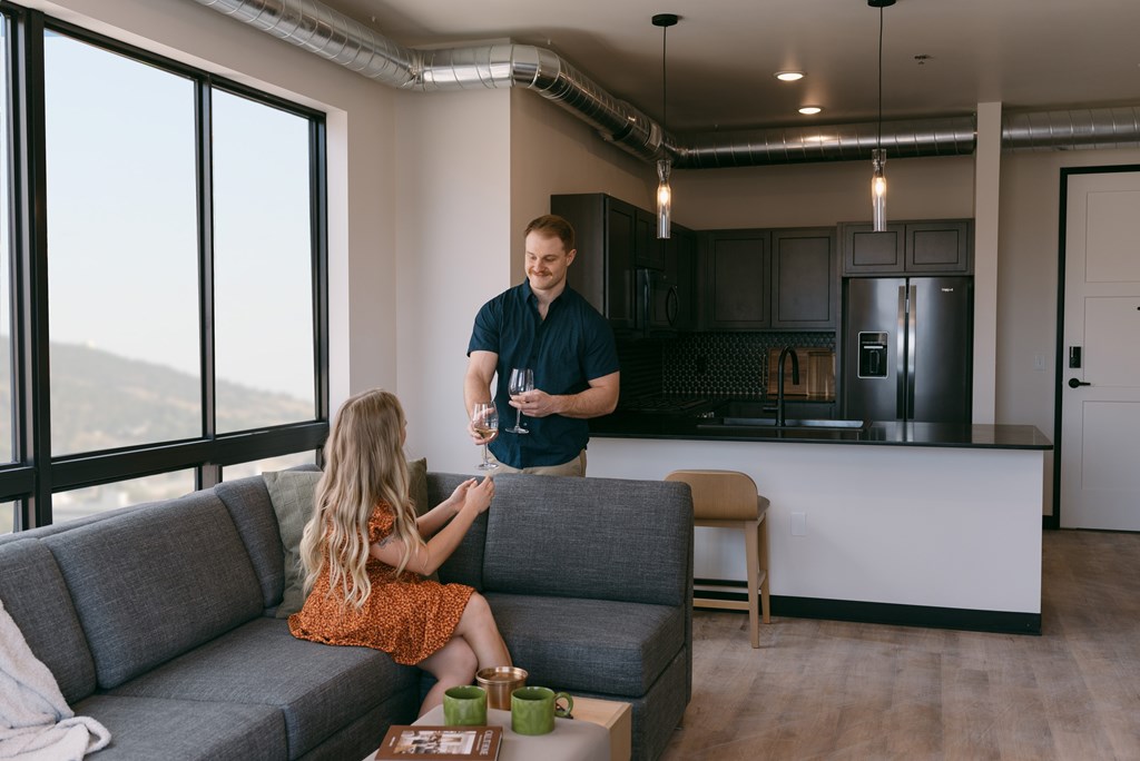 A man and a girl are sitting on a grey sofa in a modern kitchen.