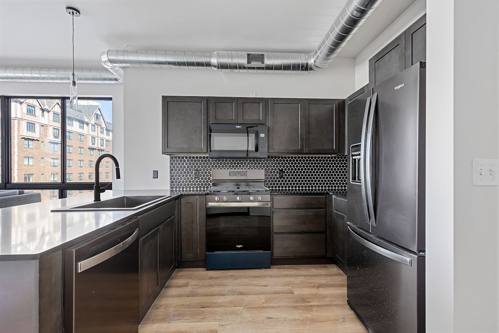 A modern kitchen with a stainless steel refrigerator and black cabinets.